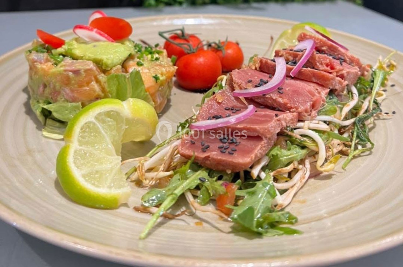 Assiette composée de thon mi-cuit sur lit de roquette, tartare de saumon à l'avocat, tomates cerises et quartiers de citron.