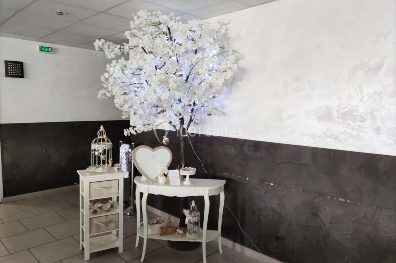 Décoration intérieure avec un arbre lumineux blanc, une table et des accessoires décoratifs dans un espace moderne.