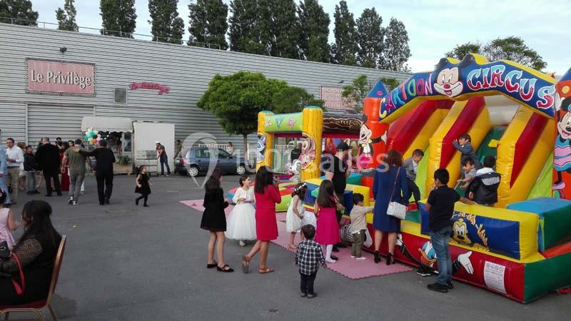 Des enfants jouent sur des structures gonflables colorées lors d'un événement en plein air devant un bâtiment.
