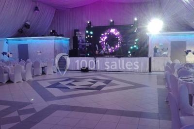 Parking vide avec marquages au sol, entouré de bâtiments industriels et d'arbres sous un ciel dégagé.