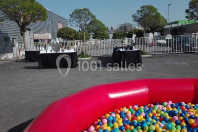 Parking vide avec marquages au sol, entouré de bâtiments industriels et d'arbres sous un ciel dégagé.