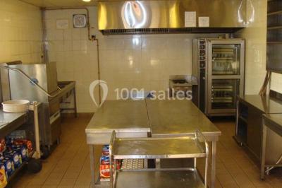 Parking vide avec marquages au sol, entouré de bâtiments industriels et d'arbres sous un ciel dégagé.