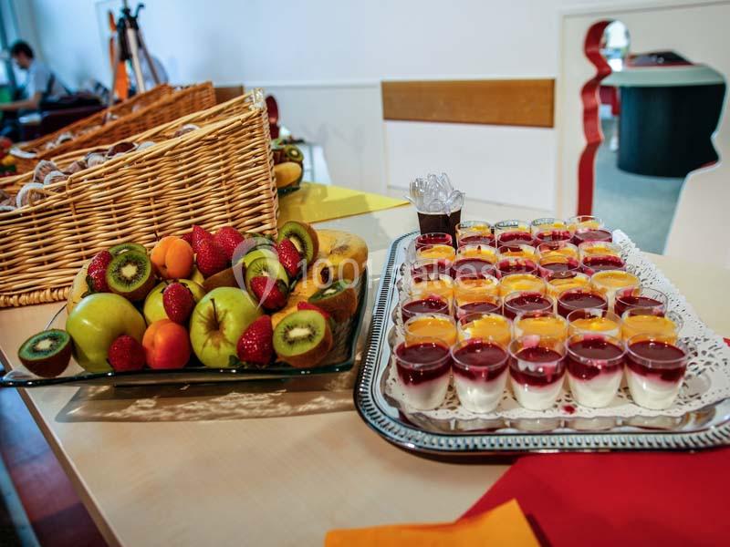 Plateau de fruits frais et verrines colorées disposés sur une table dans un cadre intérieur lumineux.