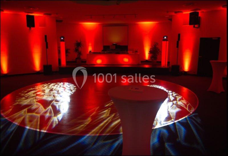 Location salle Villers-sur-Mer (Calvados) - Salle Panoramique Villers Sur Mer #8 Salle de réception éclairée en rouge avec une piste de danse illuminée et des tables hautes en premier plan.