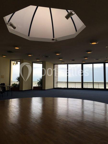 Salle lumineuse avec parquet, grandes baies vitrées donnant sur la mer et plafond en dôme avec éclairage intégré.
