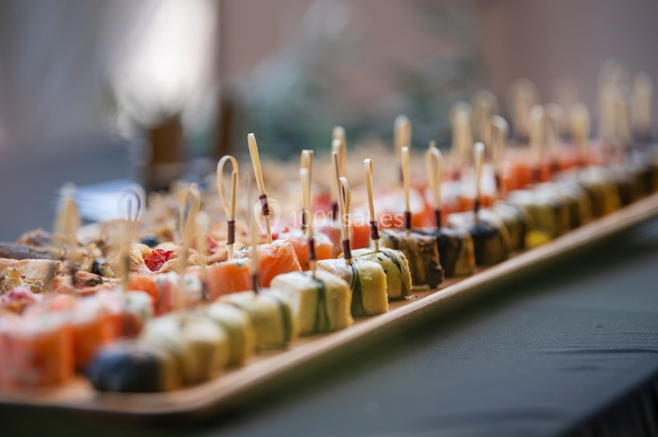 Assortiment de sushis variés alignés sur un plateau en bois, chacun décoré avec un pique en bois.