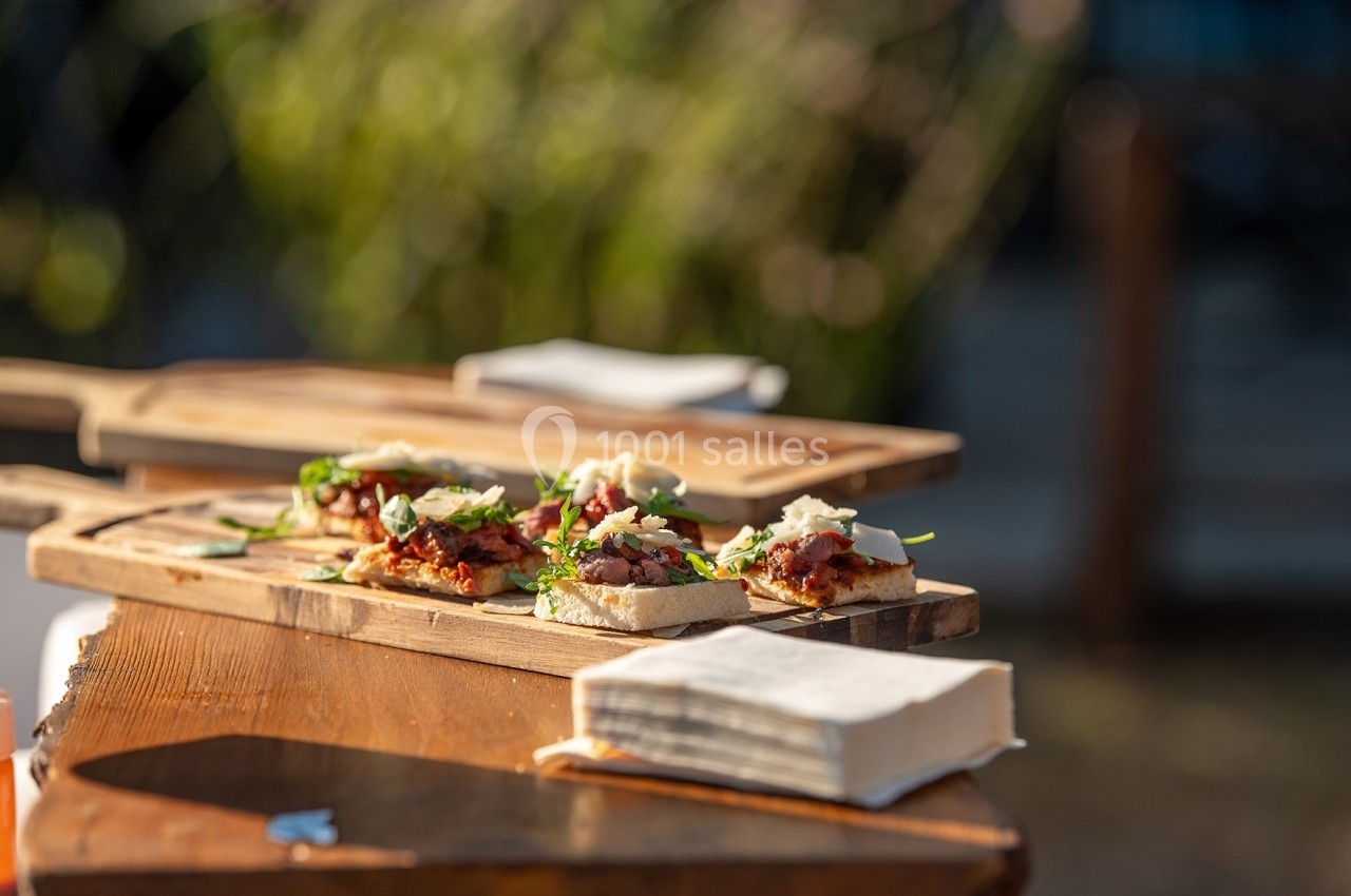 Tranches de pain garnies de légumes, fromage et herbes, servies sur une planche en bois à l'extérieur.