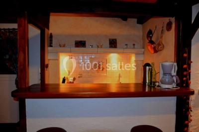 Miniature Location salle Saint-Georges-d'Espéranche (Isère) - Les Jardins du Castel #31 Cuisine rustique avec un bar en bois, éclairage chaleureux, cafetière et ustensiles suspendus au mur.