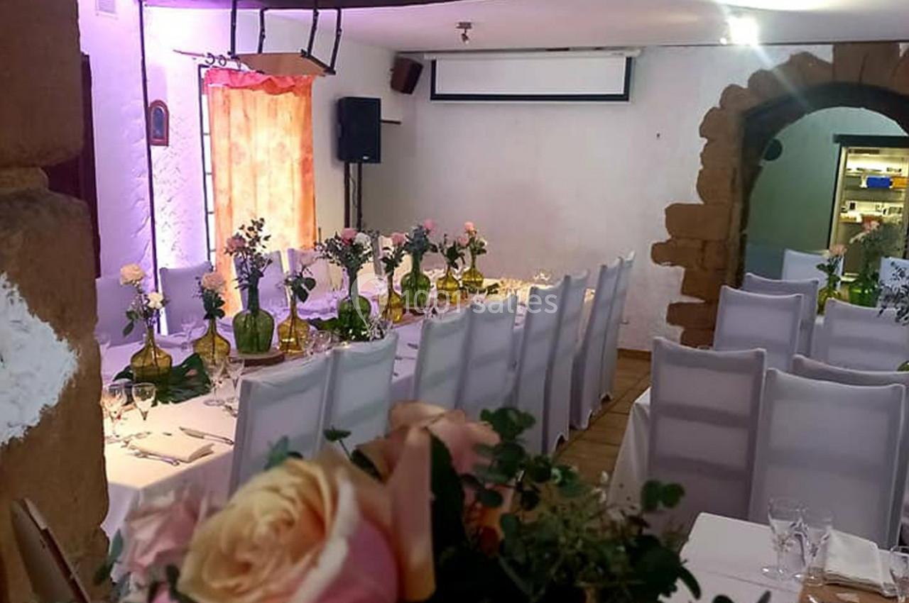 Location salle Saint-Georges-d'Espéranche (Isère) - Les Jardins du Castel #5 Salle décorée pour un événement avec des tables alignées, nappes blanches, chaises houssées et bouquets de fleurs.