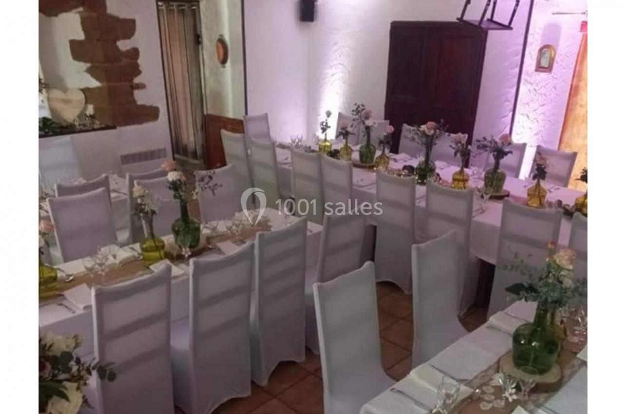Location salle Saint-Georges-d'Espéranche (Isère) - Les Jardins du Castel #6 Salle décorée pour un événement avec des tables alignées, nappes blanches, chaises houssées et centres de table fleuris.