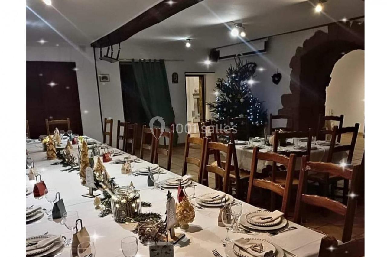 Location salle Saint-Georges-d'Espéranche (Isère) - Les Jardins du Castel #7 Grande salle décorée pour un repas festif, avec une longue table dressée et un sapin illuminé en arrière-plan.