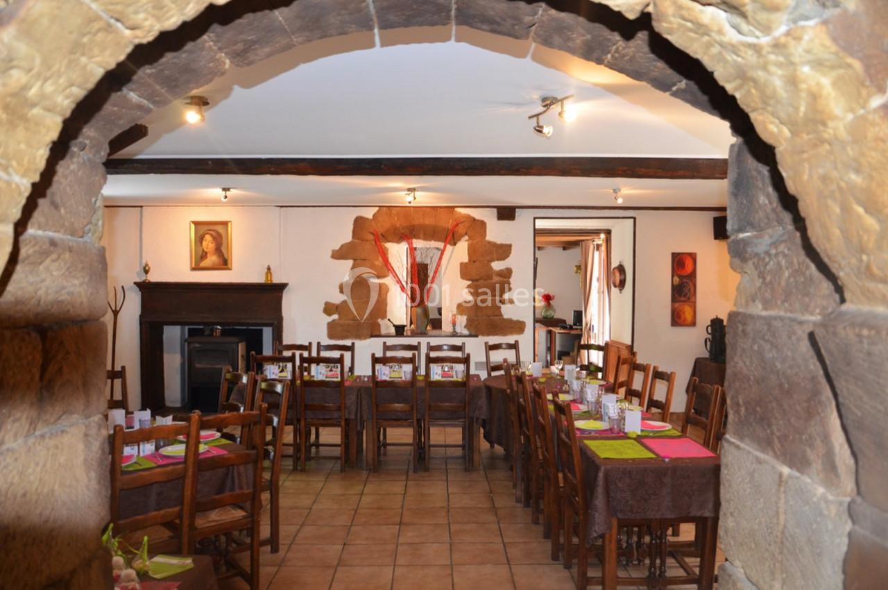 Location salle Saint-Georges-d'Espéranche (Isère) - Les Jardins du Castel #3 Salle à manger rustique avec tables en bois dressées, murs en pierre et décorations chaleureuses.