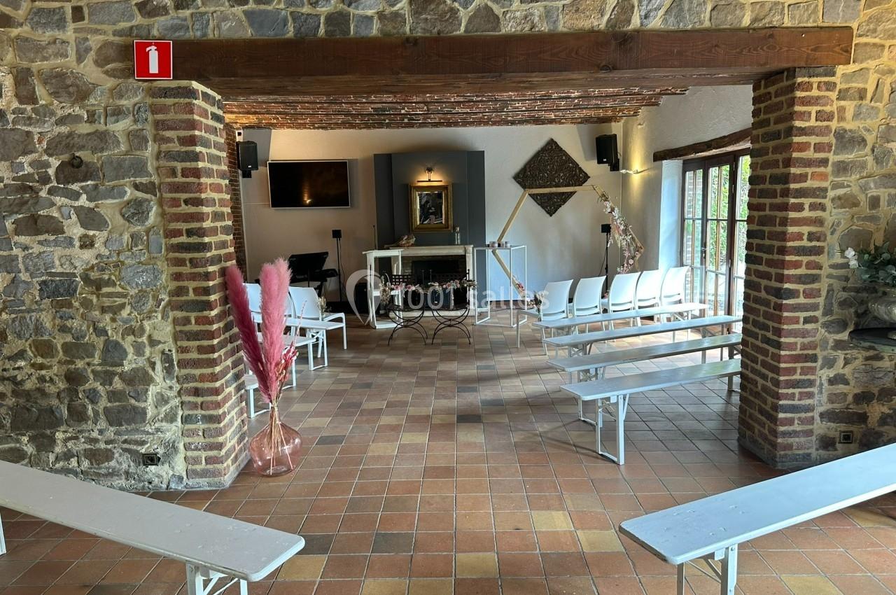 Salle avec des bancs blancs, murs en pierre et briques, décorations simples, éclairage naturel et vue sur un autel.