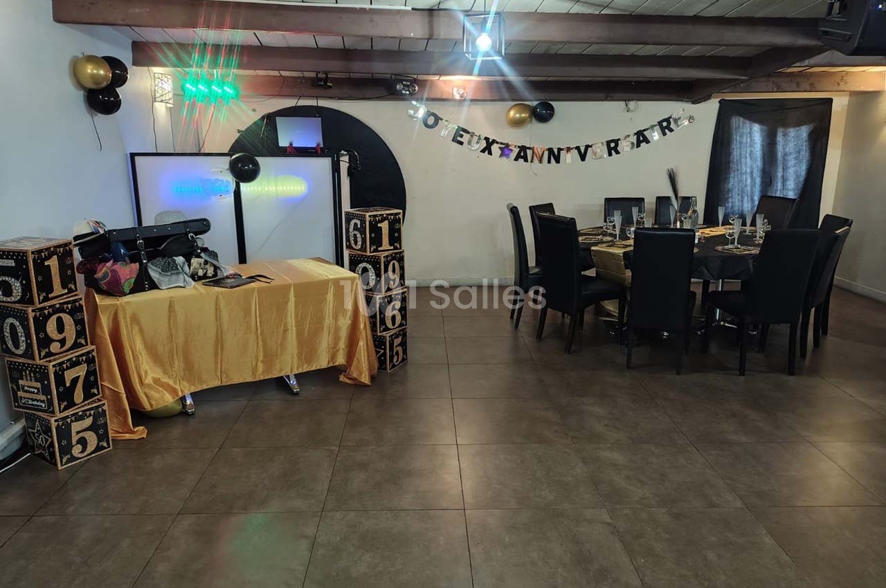 Salle décorée pour un anniversaire avec table dressée, guirlande murale, cubes décoratifs et projecteur.