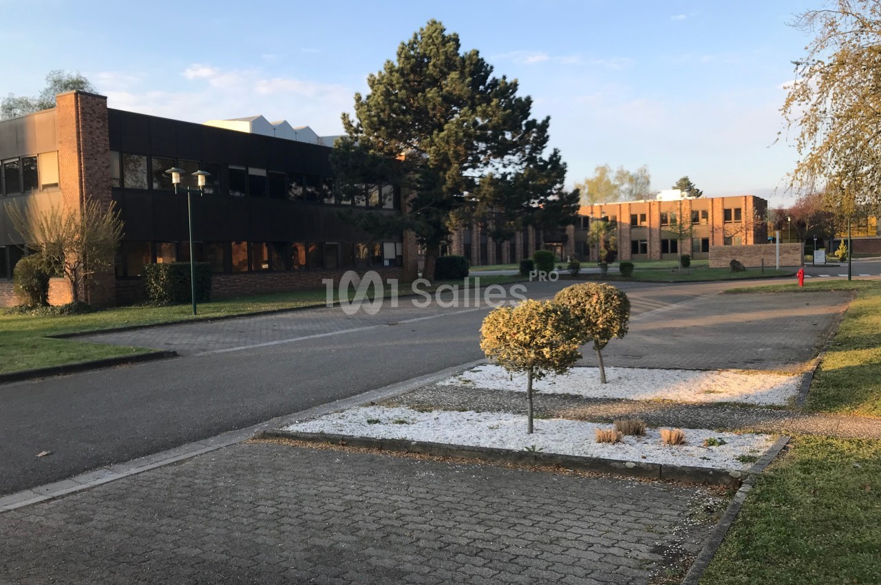Bâtiments en briques entourés d'arbres et d'espaces verts, avec une allée pavée au premier plan.