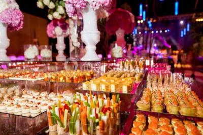 Décor intérieur avec éclairage coloré, fontaines illuminées, végétation tropicale et tables dressées en arrière-plan.