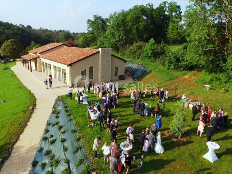 Vue aérienne d'une réception en plein air près d'un bâtiment moderne entouré de verdure.