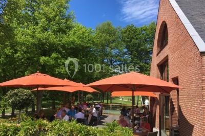 Vue nocturne d'une maison en bois éclairée, entourée d'arbres illuminés, sous un ciel nuageux avec la lune visible.