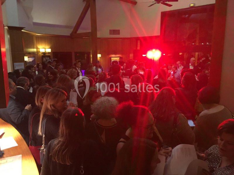 Groupe de personnes rassemblées dans une salle éclairée par des lumières rouges, discutant et tenant des documents.