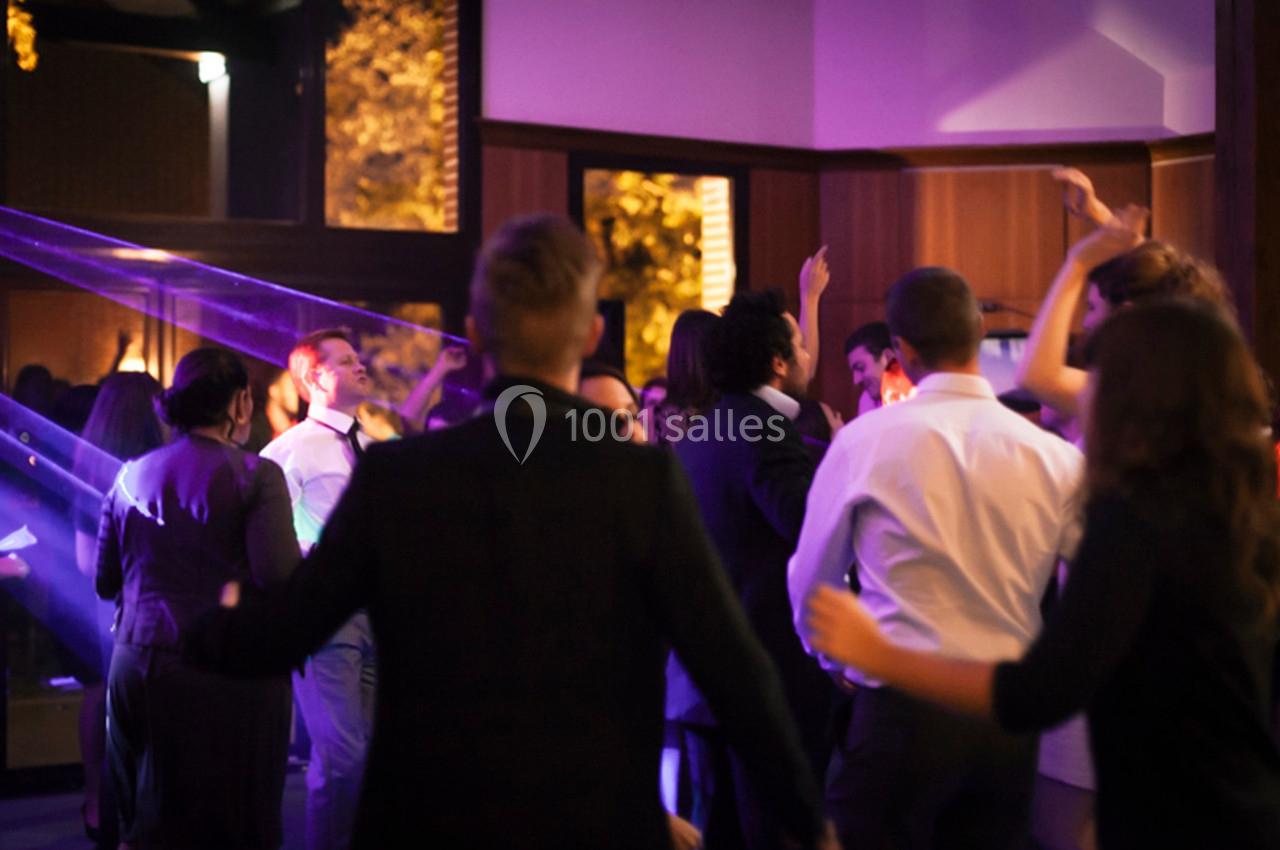 Groupe de personnes dansant dans une salle éclairée par des lumières colorées, ambiance festive en soirée.