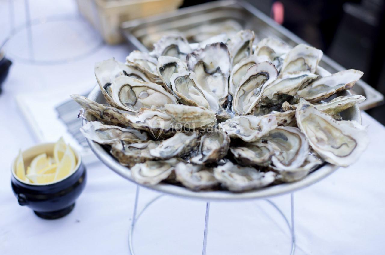 Plateau d'huîtres ouvertes disposées sur un support métallique, accompagné d'un bol de quartiers de citron.