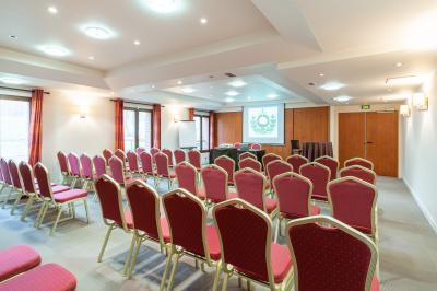 Vue nocturne d'une maison en bois éclairée, entourée d'arbres illuminés, sous un ciel nuageux avec la lune visible.
