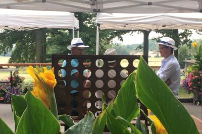 Vue nocturne d'une maison en bois éclairée, entourée d'arbres illuminés, sous un ciel nuageux avec la lune visible.