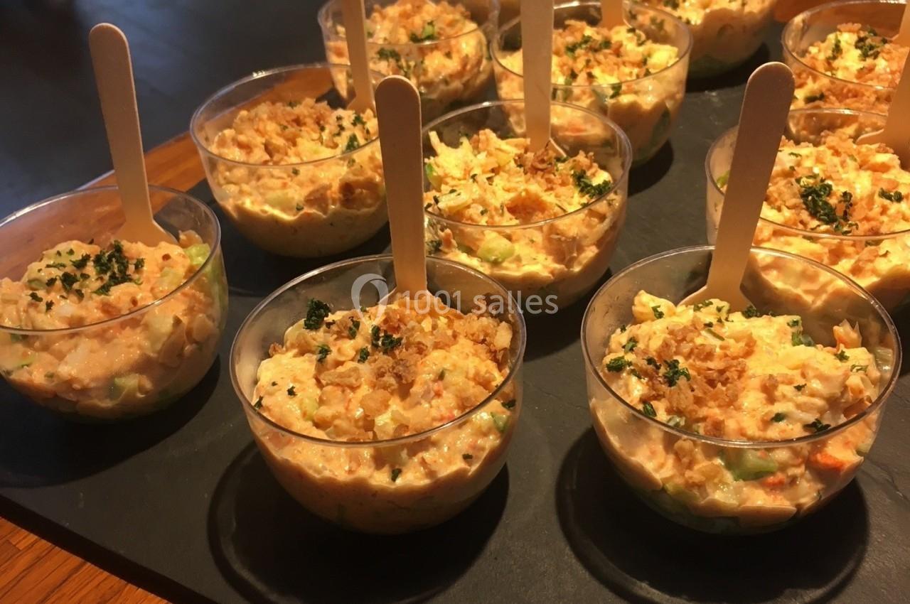 Verrines individuelles de salade crémeuse garnies de persil, servies avec des bâtonnets en bois sur un plateau.