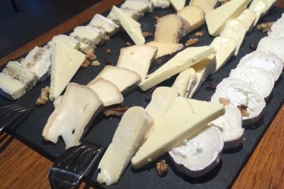 Vue nocturne d'une maison en bois éclairée, entourée d'arbres illuminés, sous un ciel nuageux avec la lune visible.