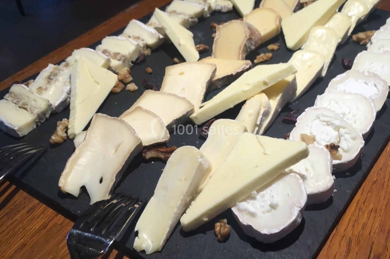 Plateau de fromages variés disposés sur une ardoise avec des fourchettes, présenté sur une table en bois.