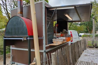 Espace extérieur décoré avec arche florale, deux chaises transparentes et fond blanc sous une tente.