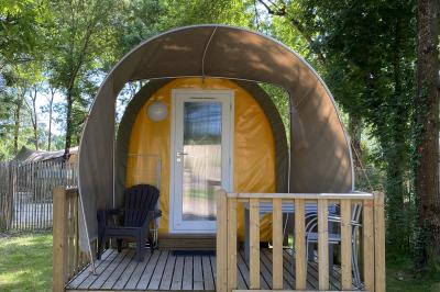 Espace extérieur décoré avec arche florale, deux chaises transparentes et fond blanc sous une tente.