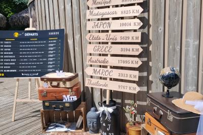Espace extérieur décoré avec arche florale, deux chaises transparentes et fond blanc sous une tente.