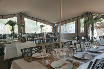 Espace extérieur décoré avec arche florale, deux chaises transparentes et fond blanc sous une tente.