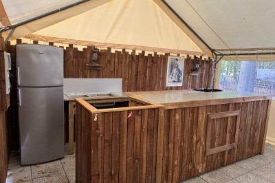 Espace extérieur décoré avec arche florale, deux chaises transparentes et fond blanc sous une tente.