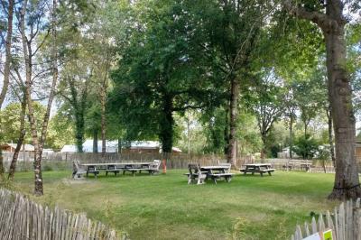 Espace extérieur décoré avec arche florale, deux chaises transparentes et fond blanc sous une tente.
