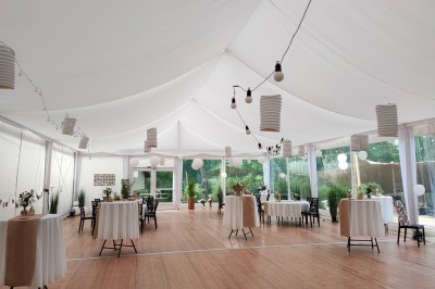 Espace extérieur décoré avec arche florale, deux chaises transparentes et fond blanc sous une tente.
