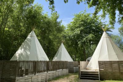 Espace extérieur décoré avec arche florale, deux chaises transparentes et fond blanc sous une tente.