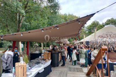 Espace extérieur décoré avec arche florale, deux chaises transparentes et fond blanc sous une tente.