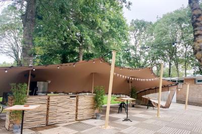 Espace extérieur décoré avec arche florale, deux chaises transparentes et fond blanc sous une tente.