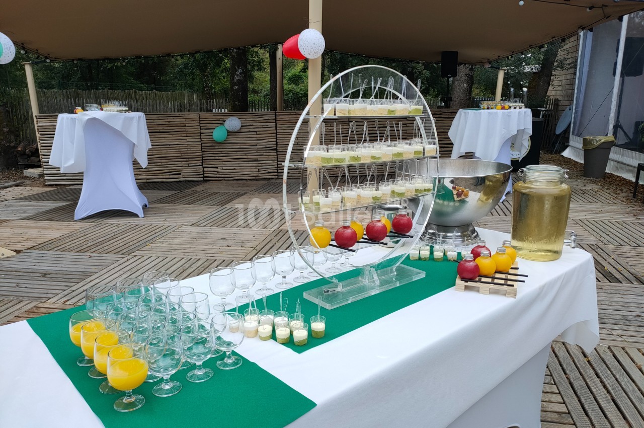 Table de buffet en extérieur avec verres de jus, desserts, fontaine à boisson et décorations festives.