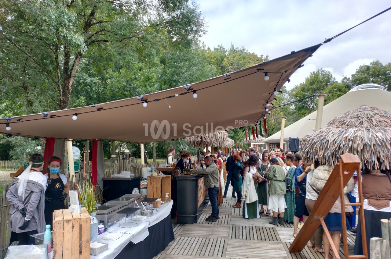 Des personnes font la queue devant un stand de restauration en plein air, sous une grande toile tendue.