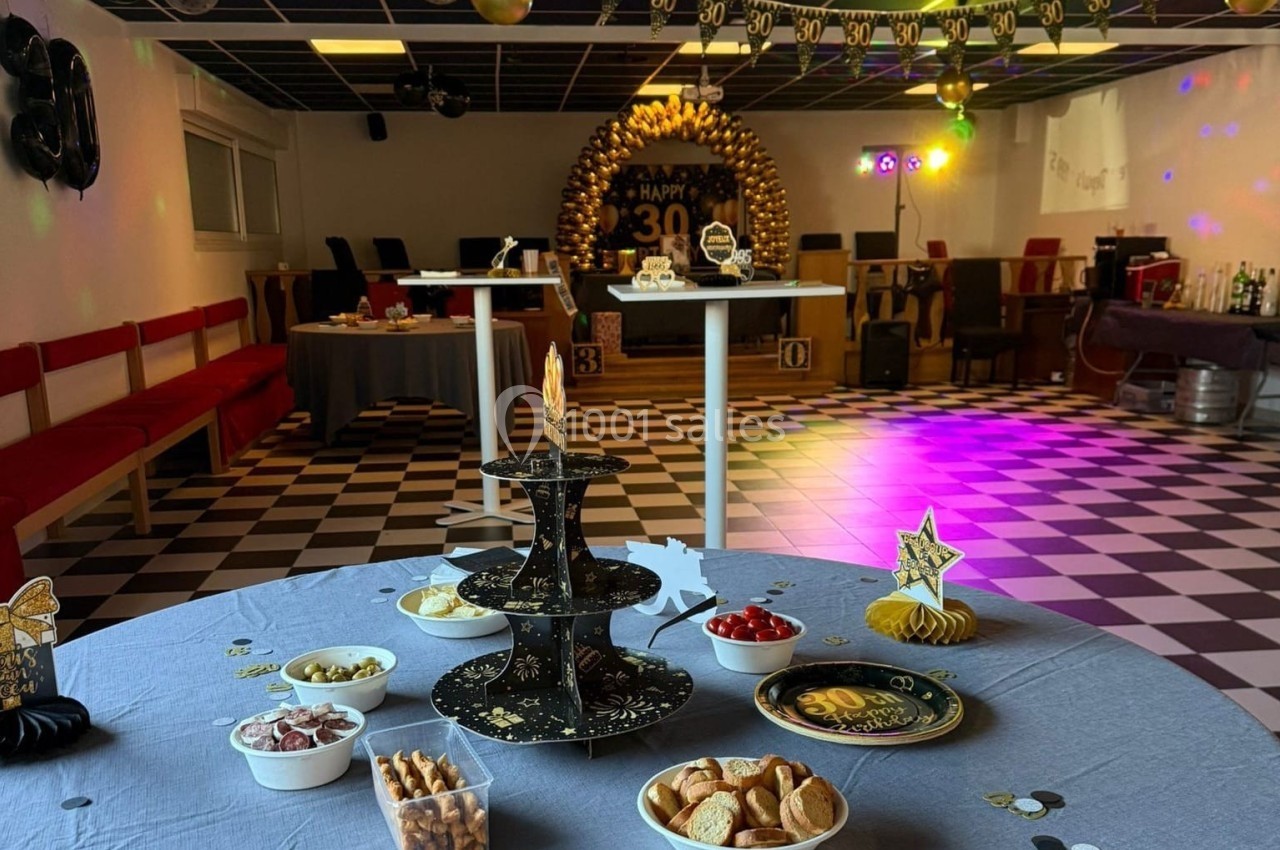 Salle décorée pour un 30e anniversaire avec table garnie de snacks et bougies, ambiance festive et éclairages colorés.