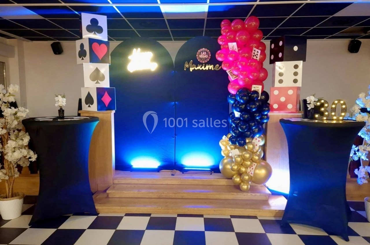 Décoration sur le thème du casino avec ballons, cartes géantes et dés, sur une scène éclairée en bleu.