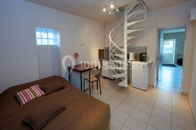 Deux réfrigérateurs professionnels vides dans une pièce carrelée avec une table en inox au premier plan.