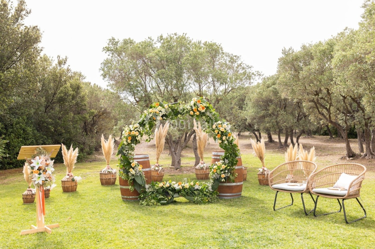 Arche florale décorée de fleurs jaunes et blanches sur une pelouse, entourée de chaises et de plantes.