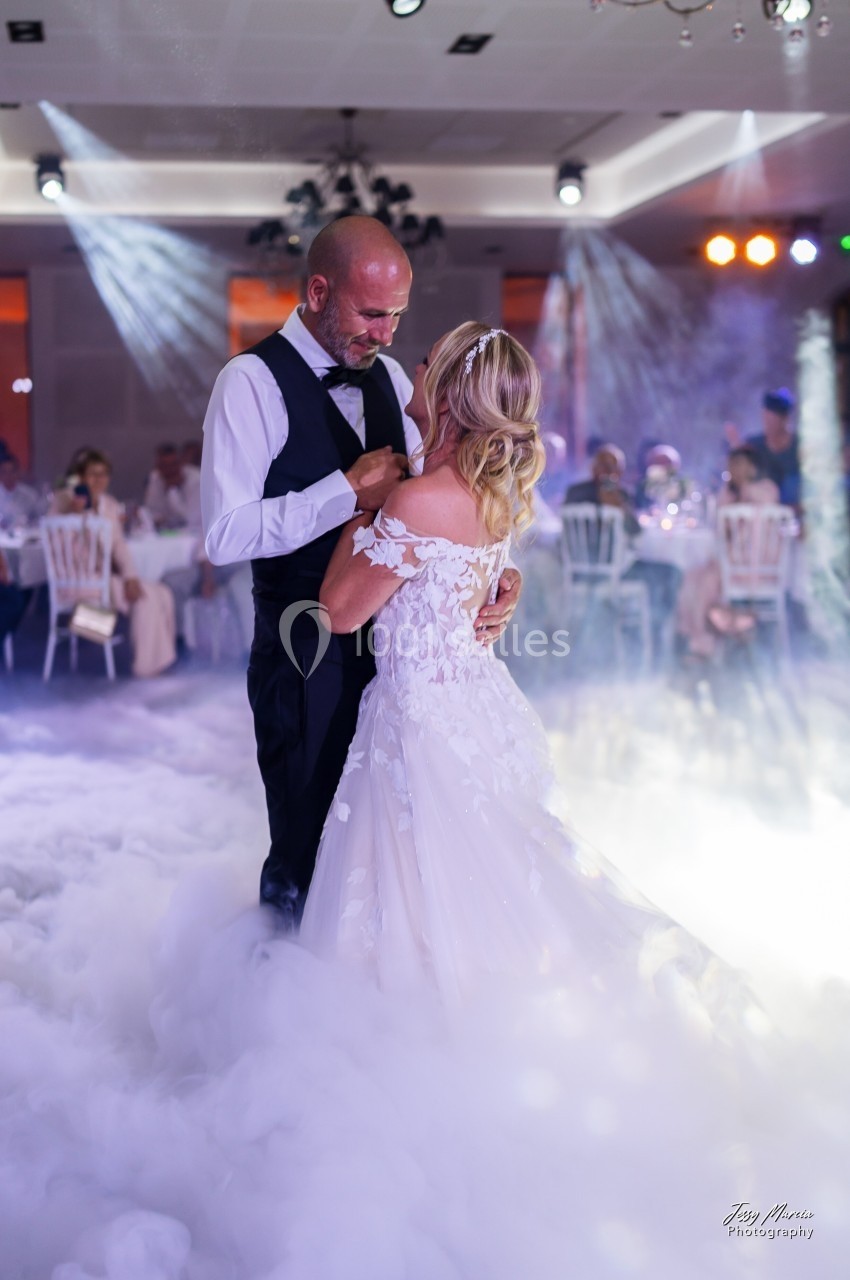Un couple danse au milieu d'une piste entourée de fumée légère, sous des éclairages tamisés.