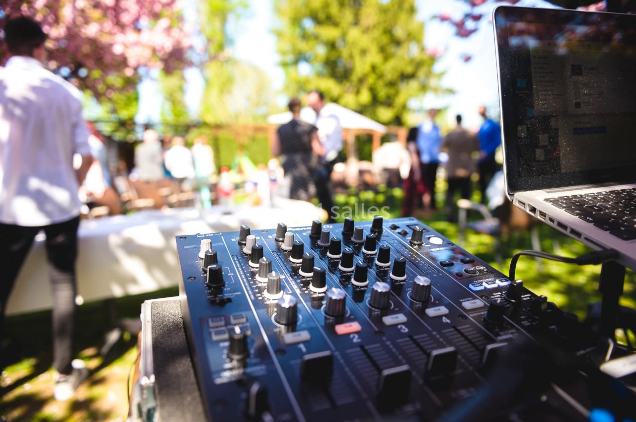 Table de mixage en extérieur lors d'un événement en plein air, avec des invités flous en arrière-plan.