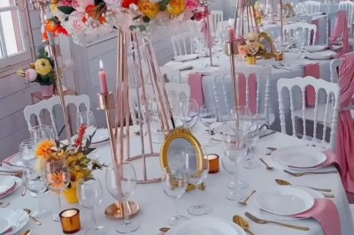 Salle de réception élégante avec décoration noire et dorée, tables dressées et bougies allumées.