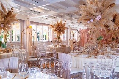 Salle de réception élégante avec décoration noire et dorée, tables dressées et bougies allumées.